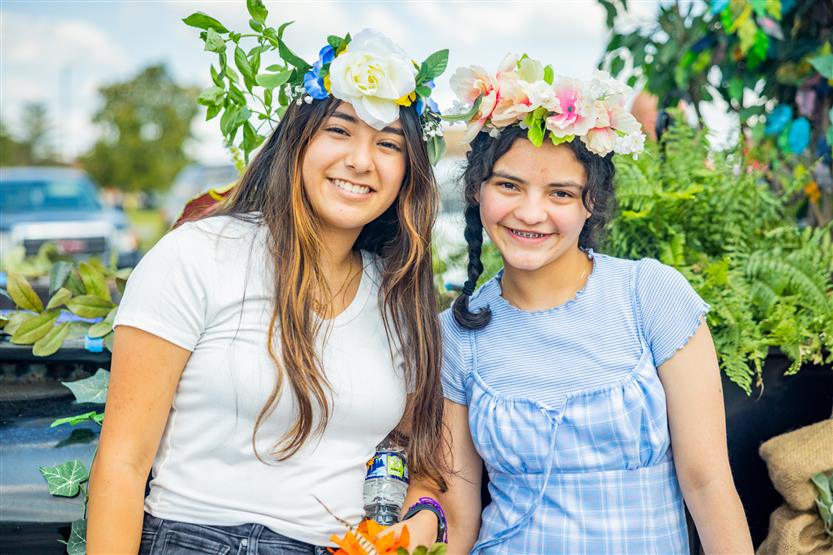 Two girls smile while wearing flower crowns